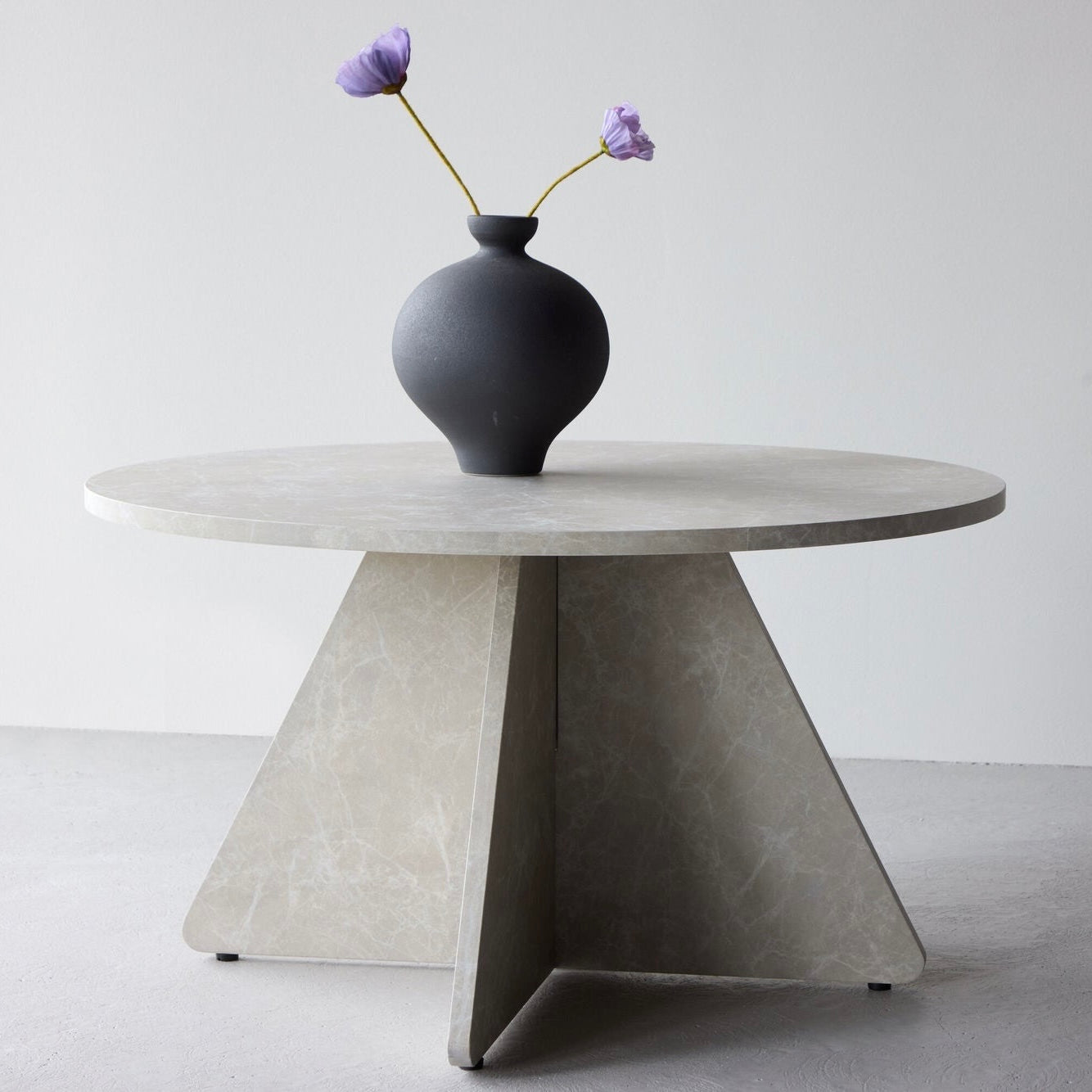 Runder Couchtisch in beiger Marmor-Optik mit ausgestelltem Untergestell, skulpturale Form aus MDF